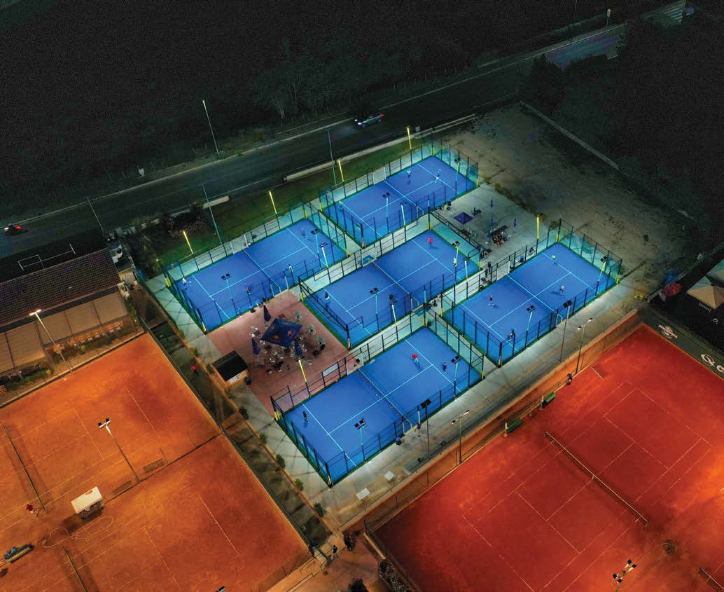 Zone sportive extérieure (terrains de padel) en gazon synthétique, éclairage nocturne.