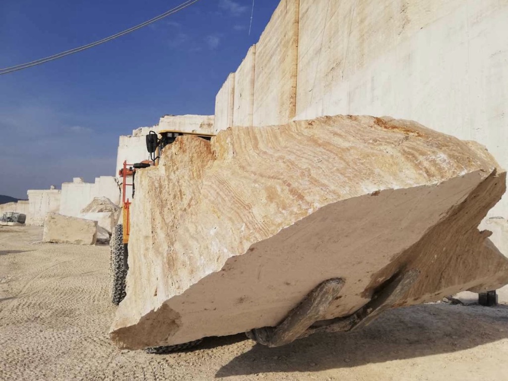 Bloc de travertin en cours d'extraction en carrière, engin de manutention.